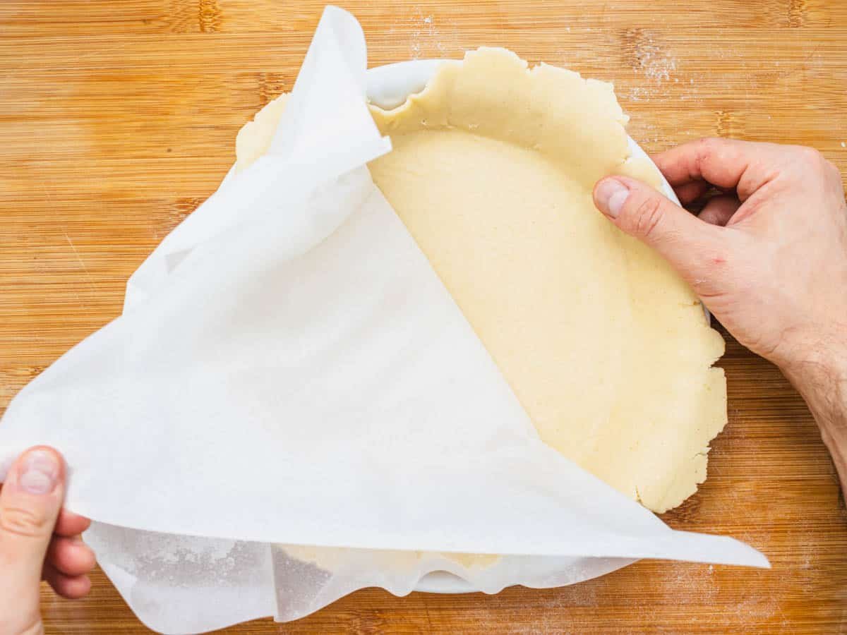 vegan pie crust in a white pie plate and hands