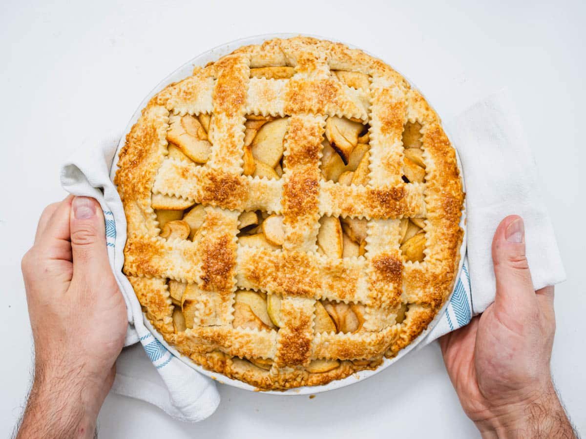 vegan apple pie after baking with hands and kitchen towel