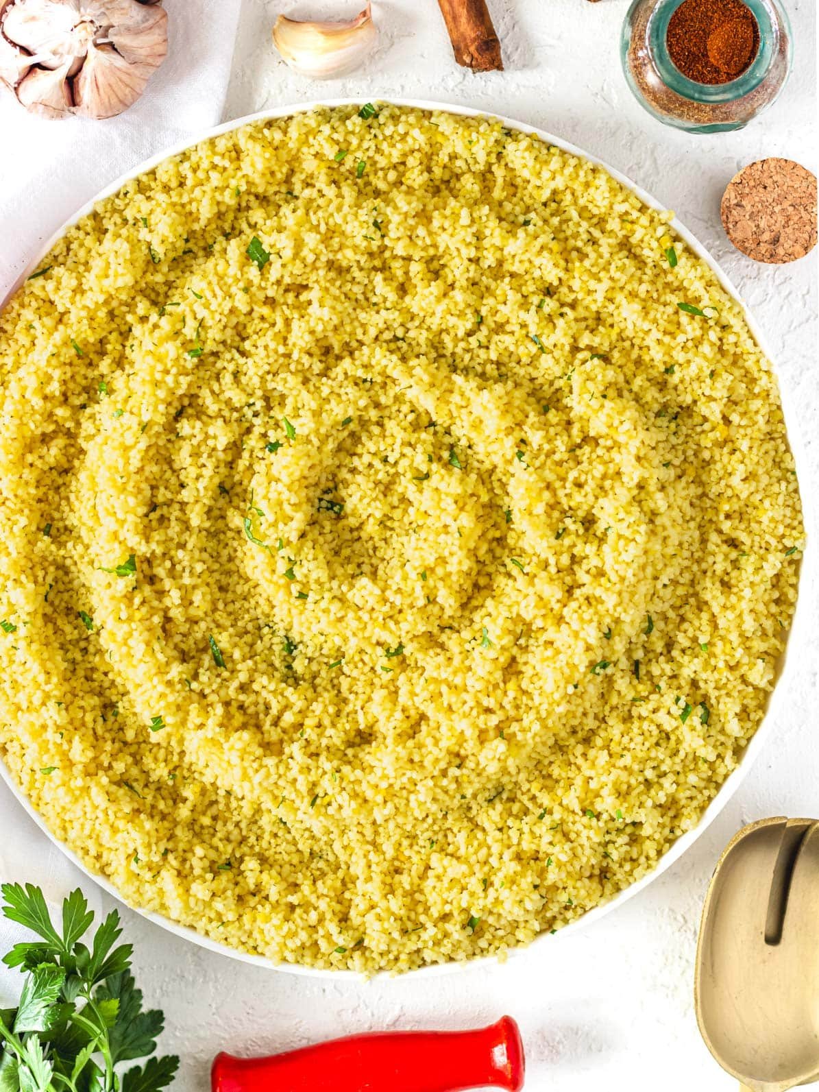 couscous with spices served on a plate with fresh parsley on the side