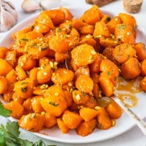 Moroccan carrot salad on a white plate with a golden spoon