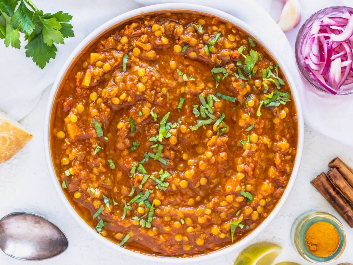 Moroccan lentil soup in a white bowl with chopped parsley