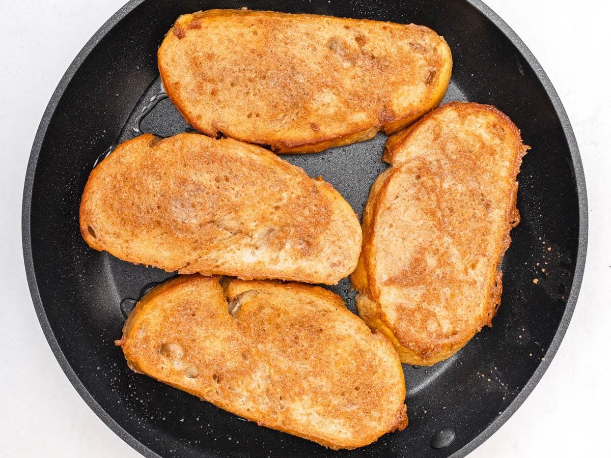 cinnamon batter covering 4 slices of bread in a skillet