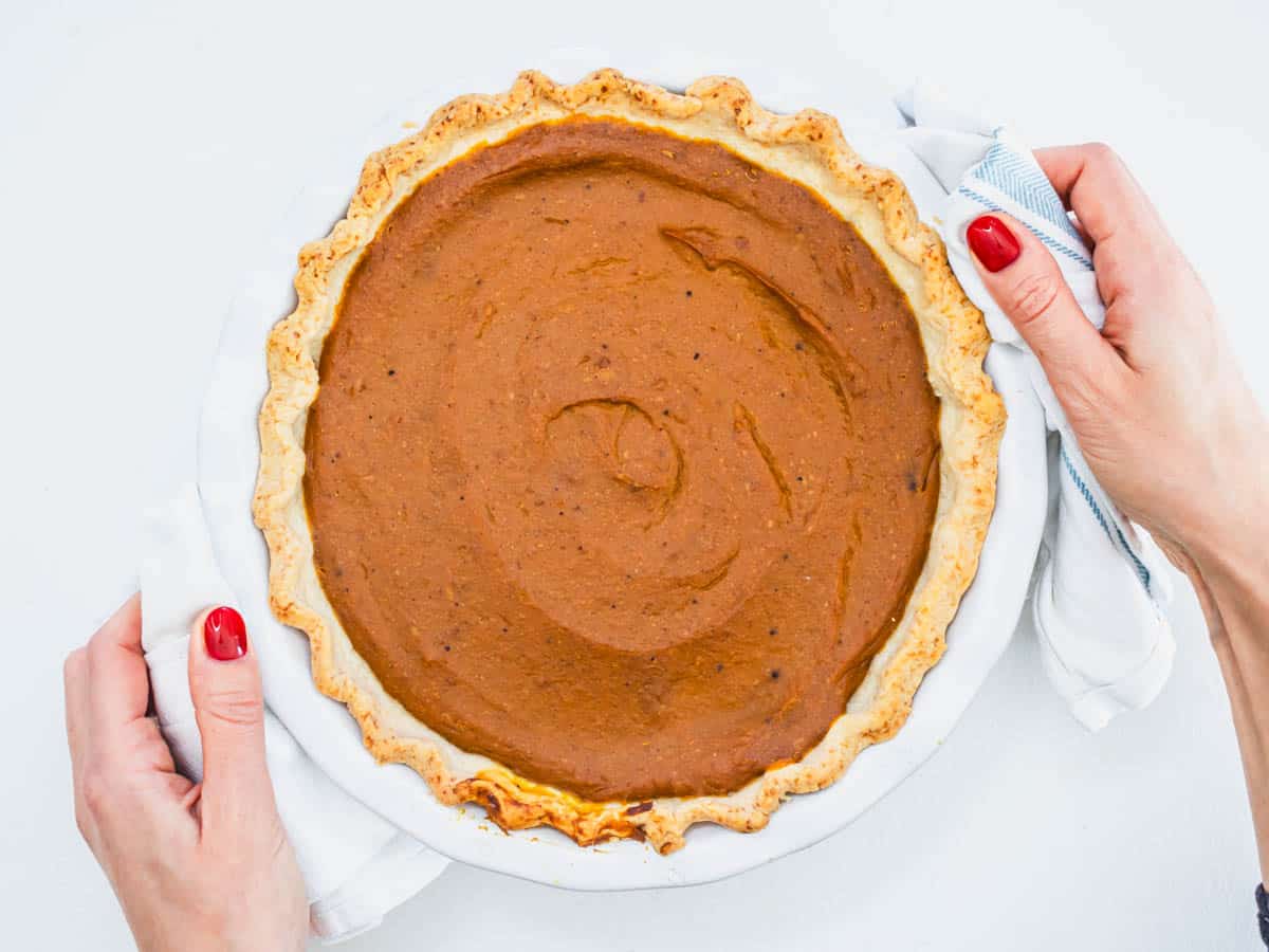 Vegan pumpkin pie after baking with hands