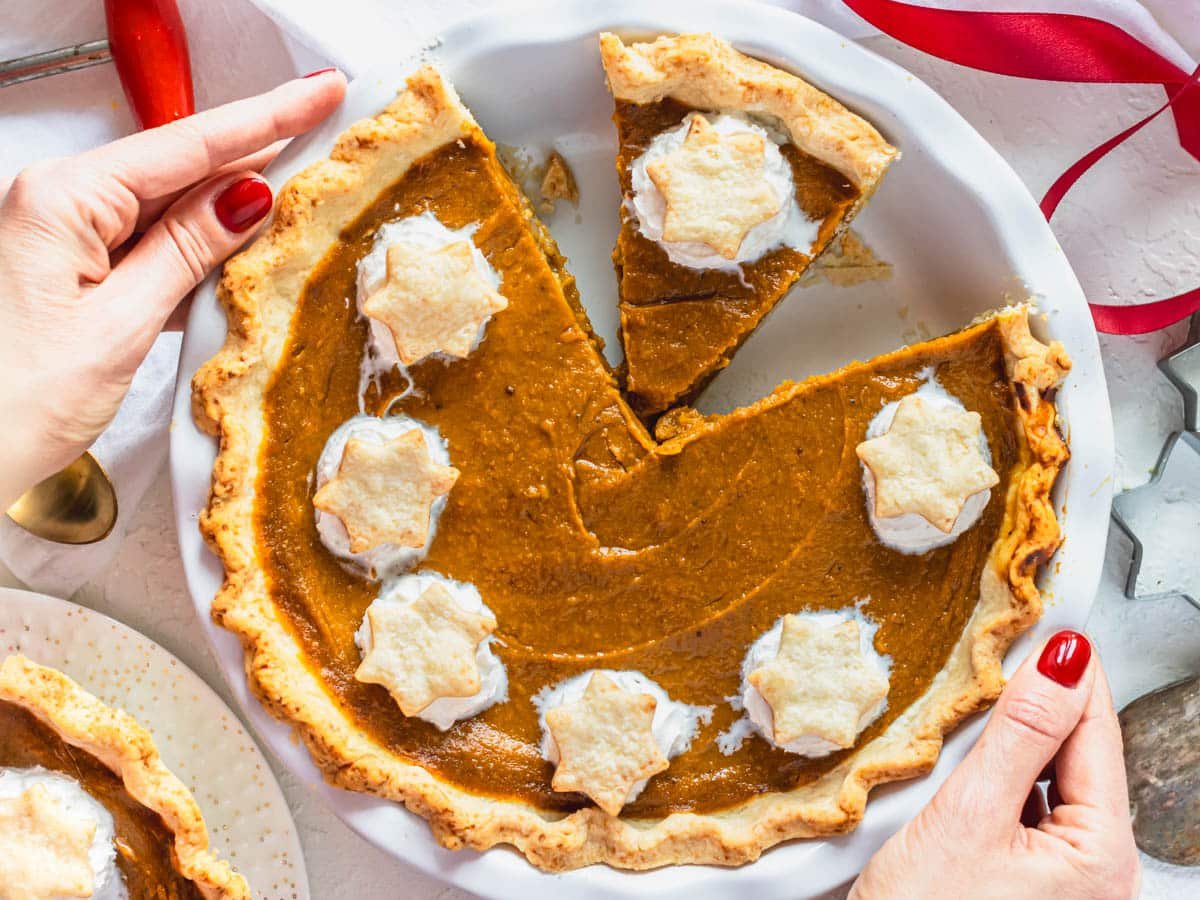 Vegan pumpkin pie with hands and red nails
