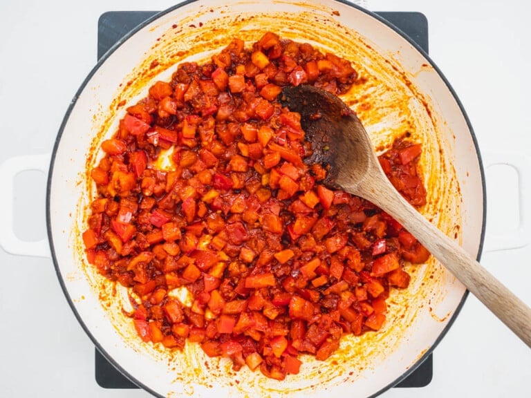diced tomato in a skillet with a wooden spoon