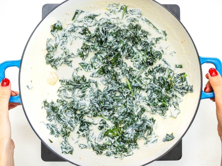 kale leaves with ricotta sauce in a skillet and hands