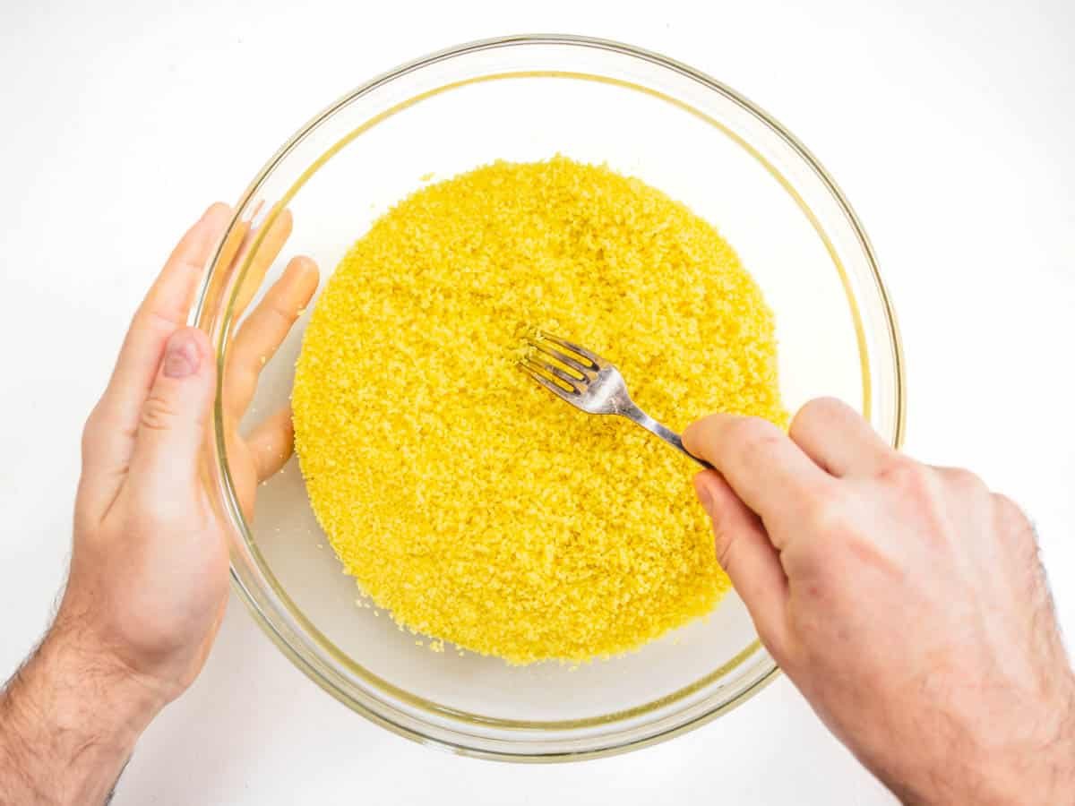 raking the couscous with a fork to fluff it up