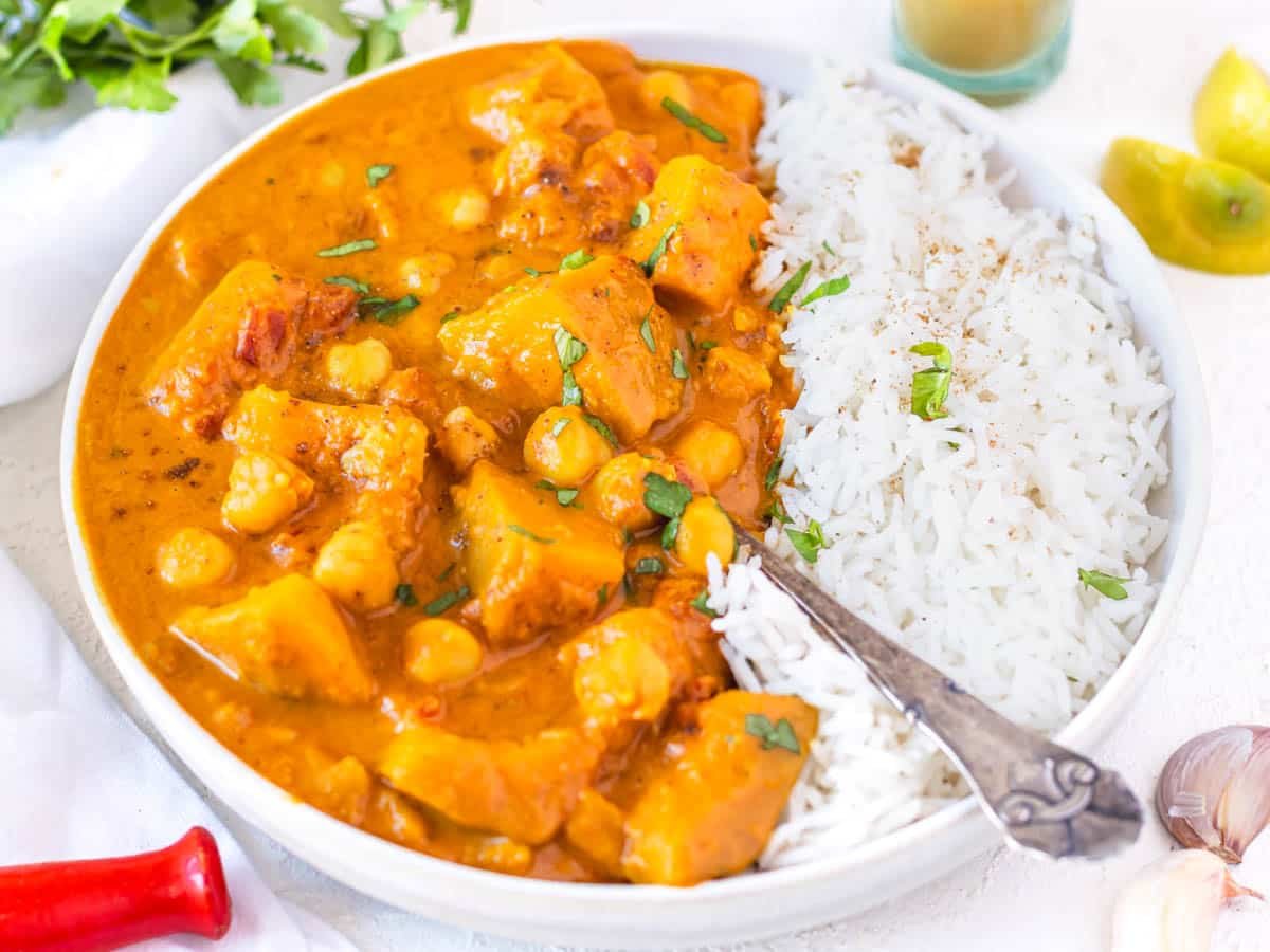 Pumpkin curry with rice, spoon and fresh parsley