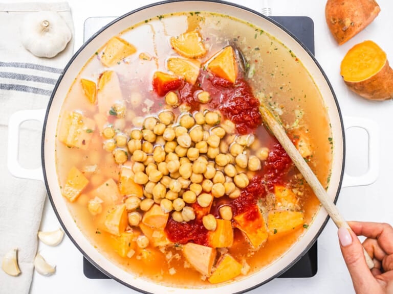 chickpeas, sweet potato and vegetable broth in a skillet with a wooden spoon