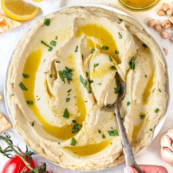 Hummus without tahini on a plate with a spoon and fresh parsley