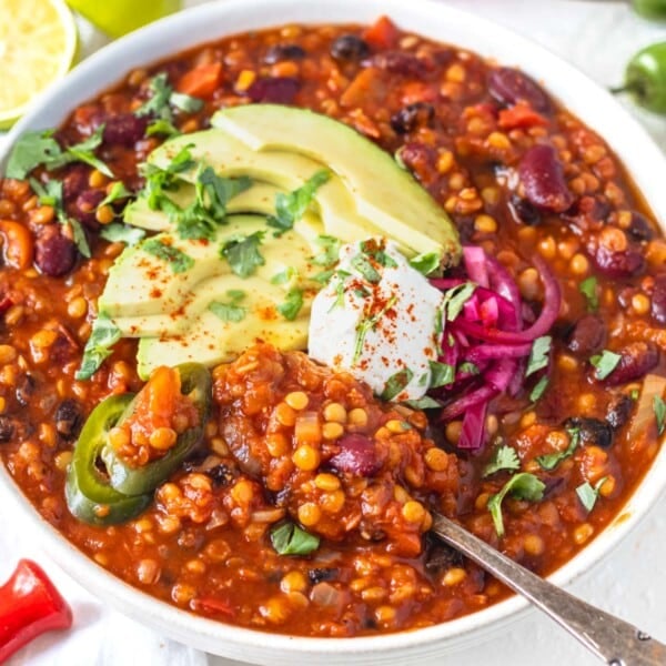 Lentil chili with sour cream, avocado slices and a silver spoon