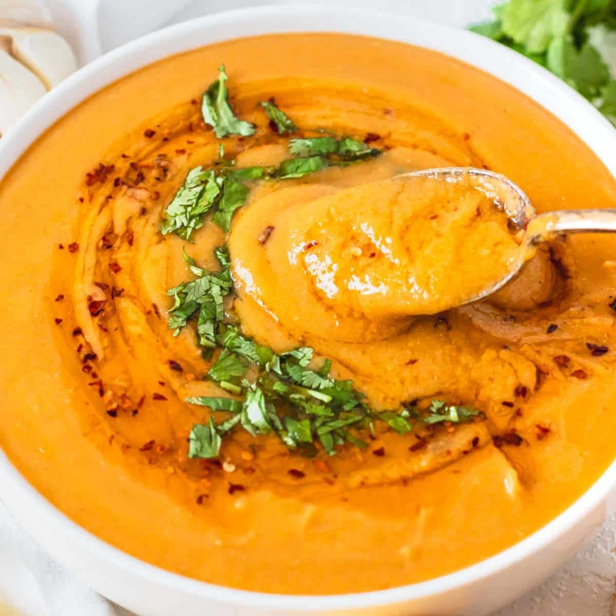 Creamy Turkish red lentil soup with a silver spoon and chili oil