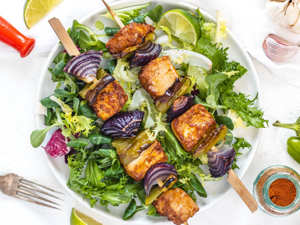 Baked Tofu skewers on salad with a fork