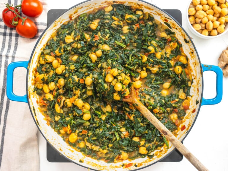 cooked chickpeas and spinach in a blue skillet with a spoon