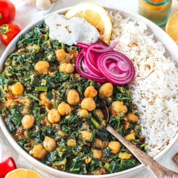 Chana Saag in a white bowl with rice and a dollop of yogurt
