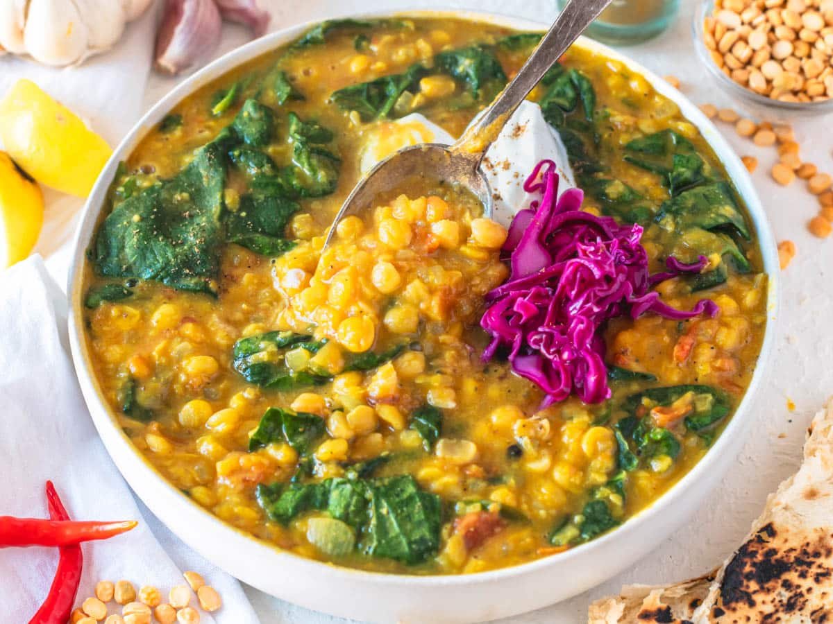 Chana dal with a silver spoon, pickled cabbage and spinach