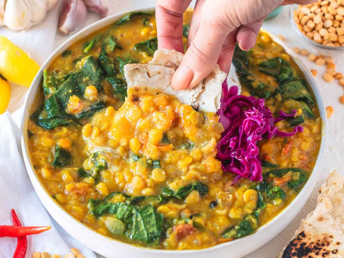 Chana dal with spinach and hand holding chapati bread