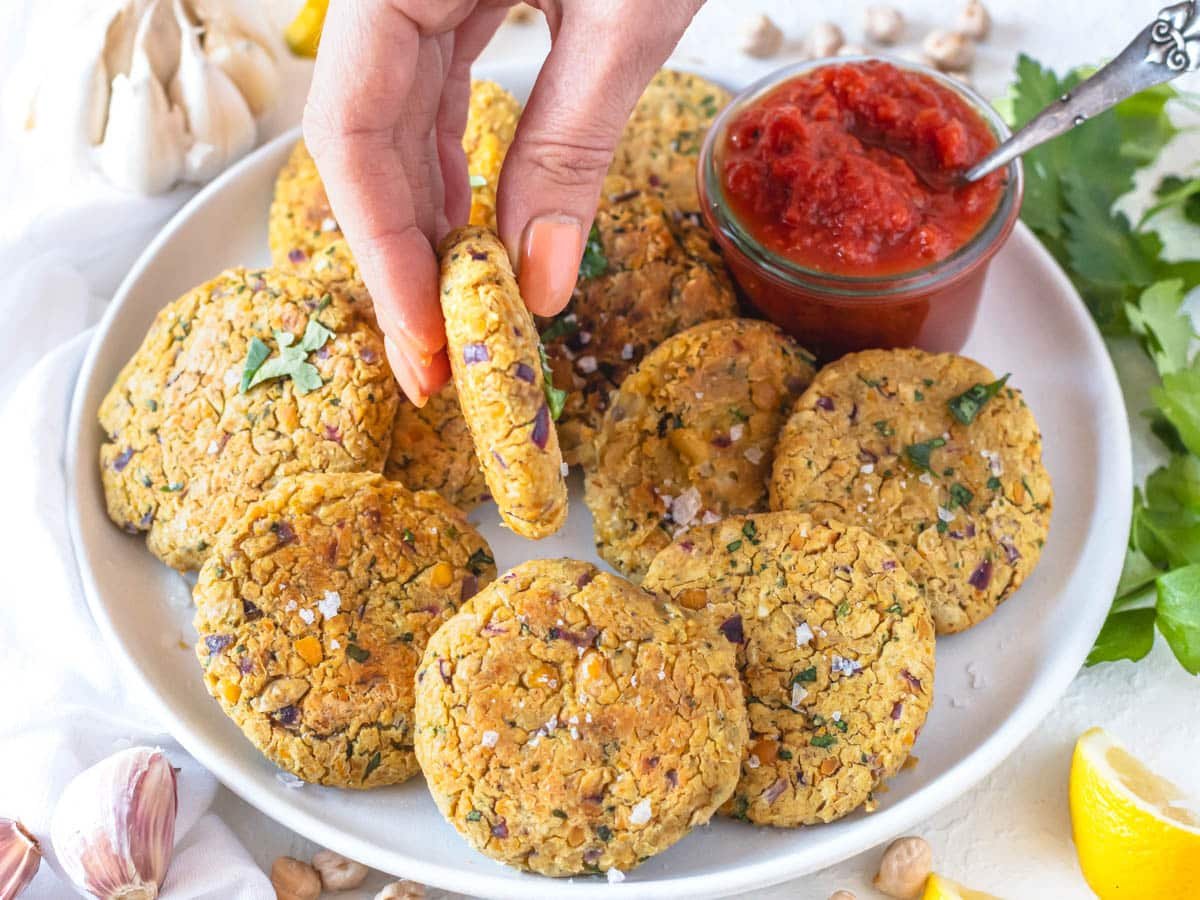 Chickpea fritters with marinara sauce and a hand holding a fritter