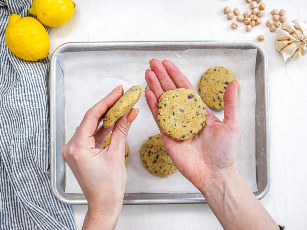 hands shaping chickpea fritters and a baking tray