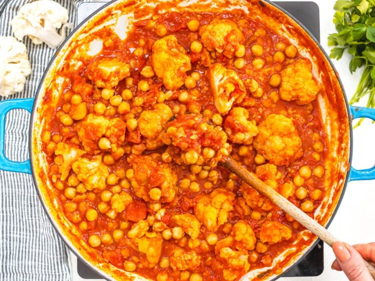 Moroccan chickpea stew after simmering with hand holding a spoon