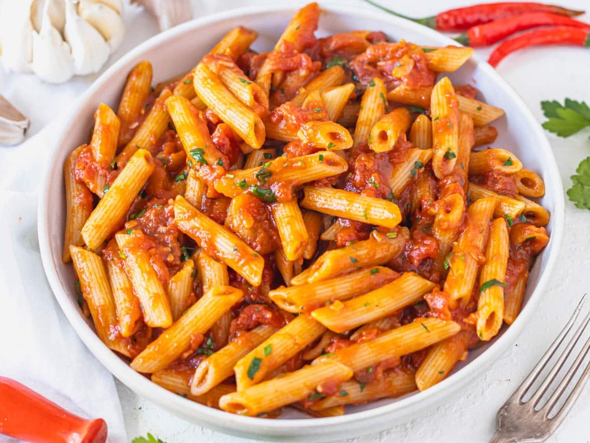Penne Arrabbiata in a white bowl with fresh parsley