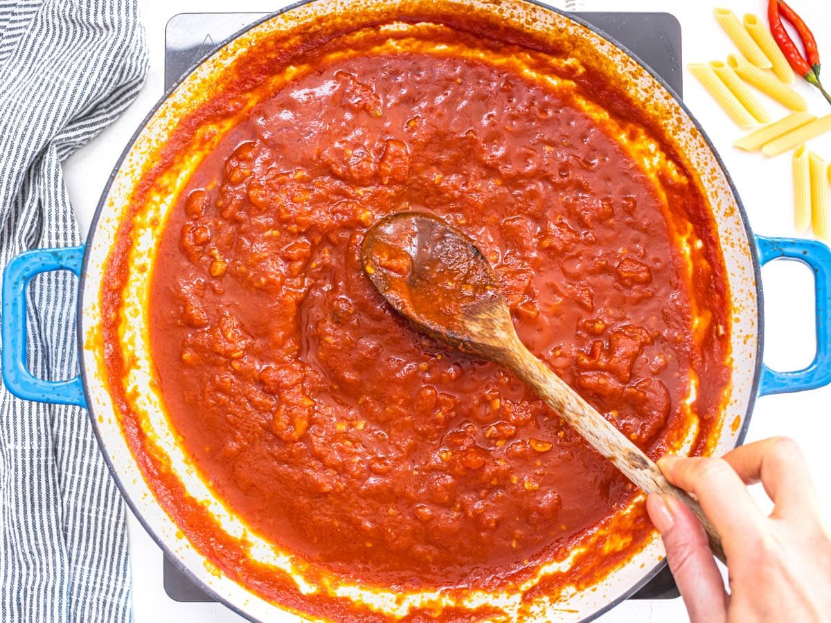 arrabbiata sauce in a blue skillet with a wooden spoon