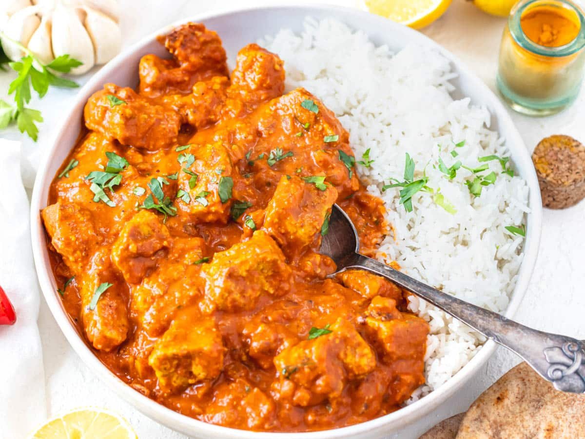 tofu tikka masala with white rice and a silver spoon