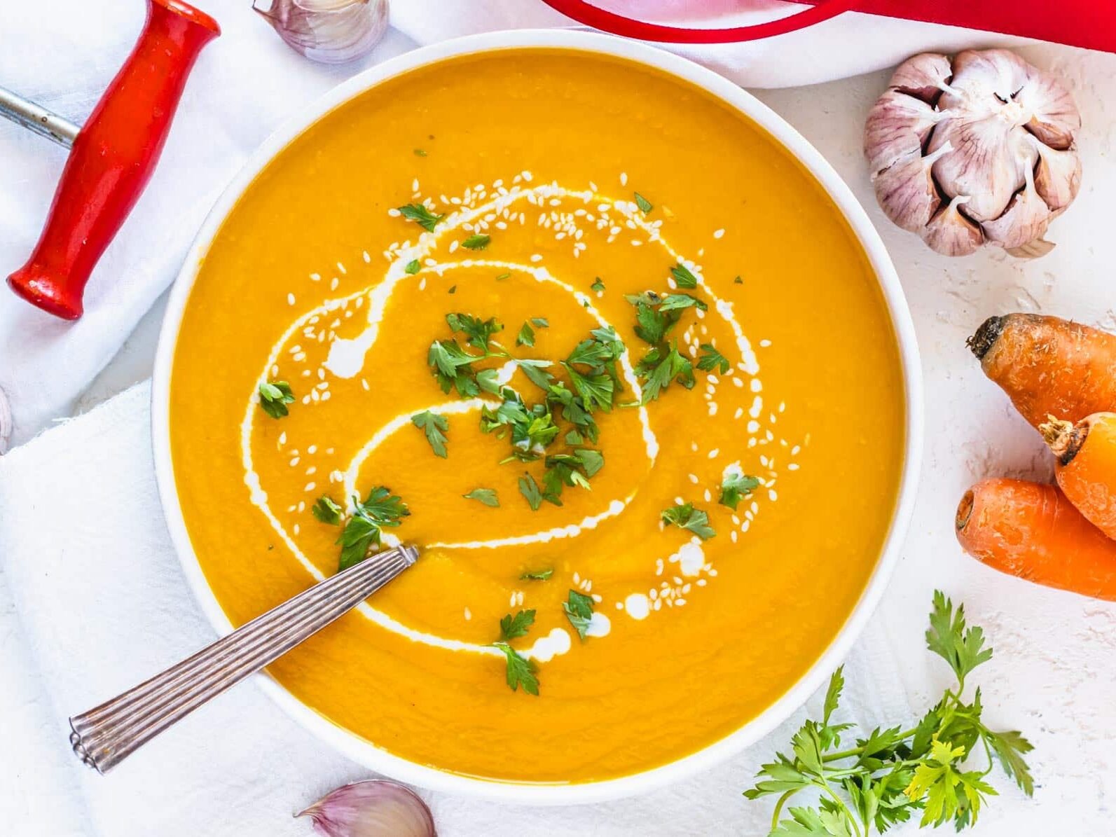 carrot soup in a white bowl with silver spoon