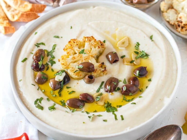 cauliflower soup with extra virgin olive oil and roasted cauliflower in a white bowl