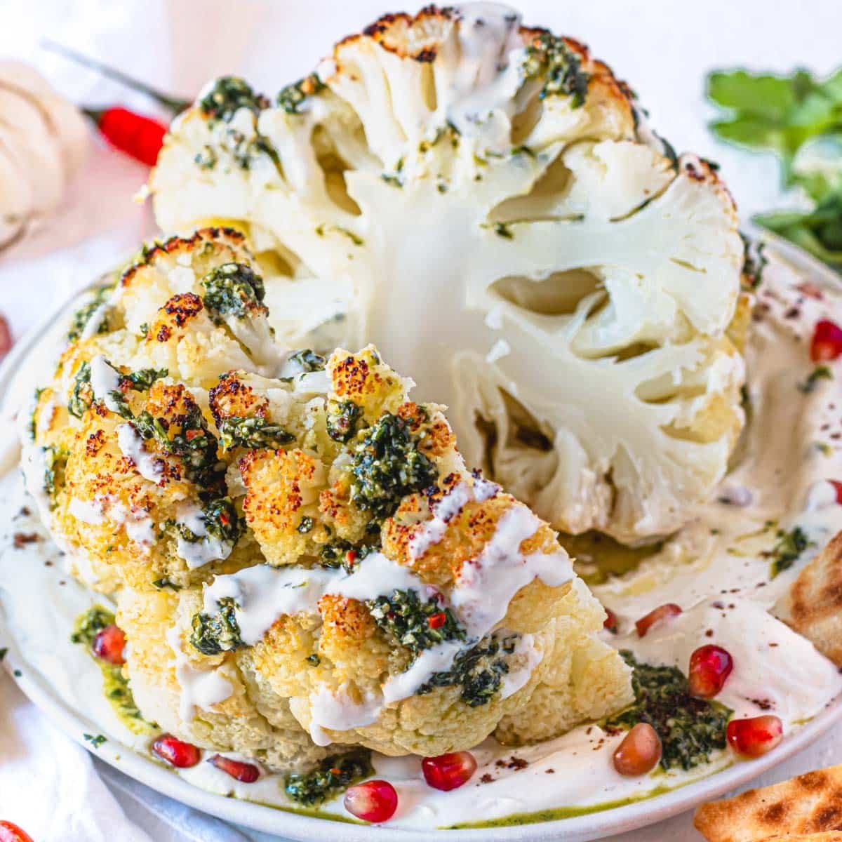 whole roasted cauliflower cut in half with a green chermoula sauce