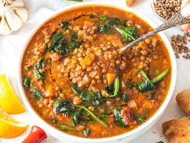 Easy lentil vegetable soup with a silver spoon in the bowl and bread on the side