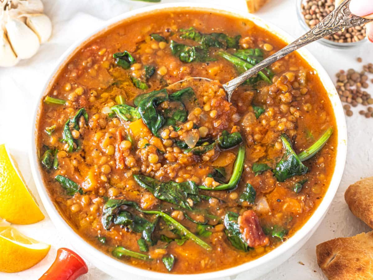 Easy lentil vegetable soup with spinach leaves and pita bread on the side
