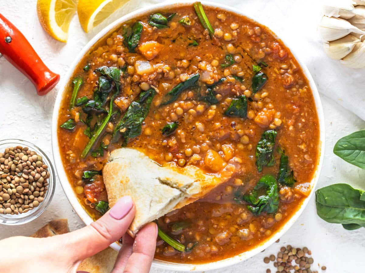 Easy lentil vegetable soup with hand holding pita bread 
