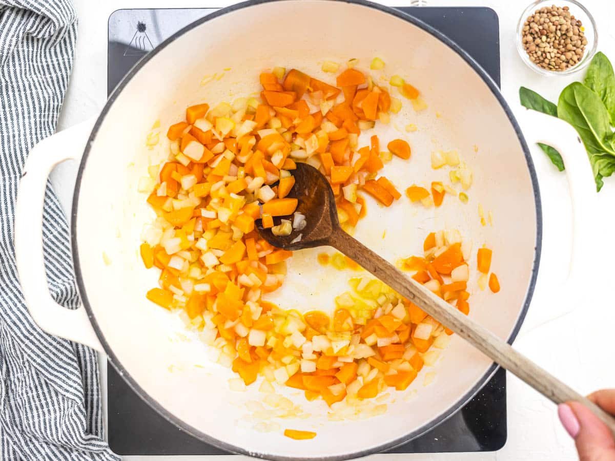 carrots and onion in a white pot frying