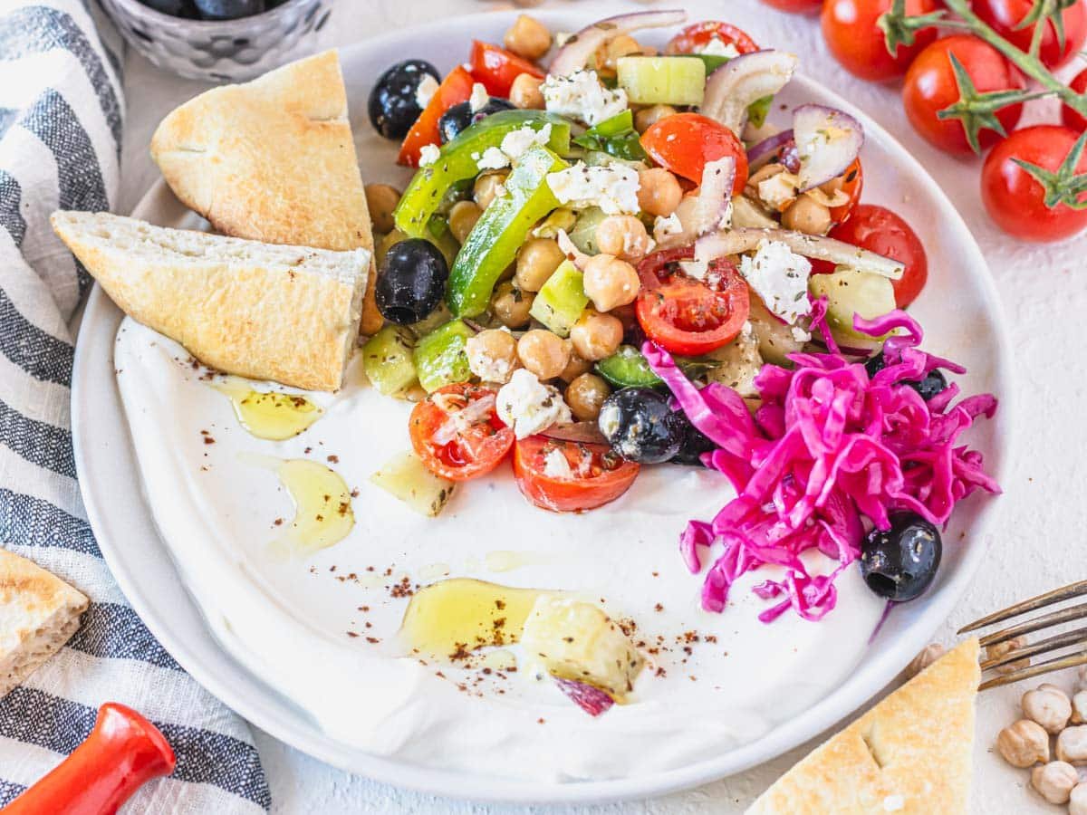 Greek chickpea salad with yogurt, pickled cabbage and pita bread on a plate
