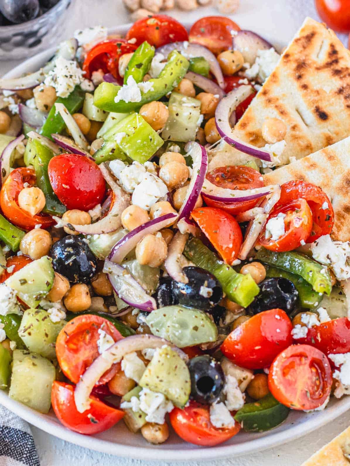 Greek chickpea salad on a white plate with pita bread