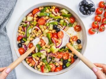 hands mixing chopped vegetables in a white bowl