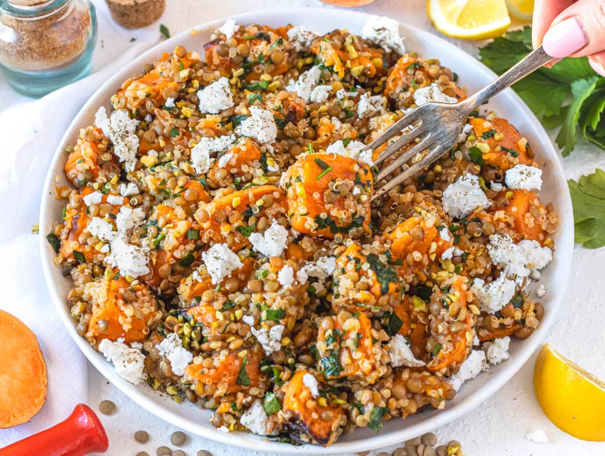 Lentil quinoa salad with feta and hand holding a fork