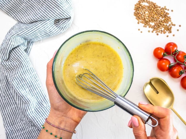 Cumin and honey mustard dressing in a bowl with a whisk