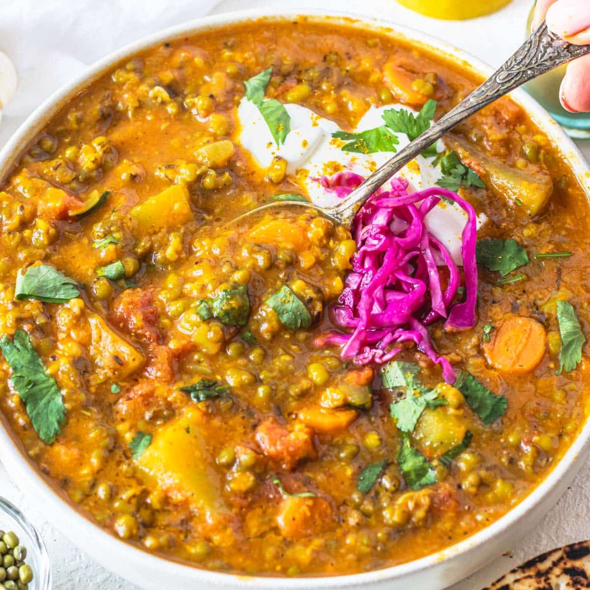 Mung bean soup with pickled cabbage and hand holding a silver spoon