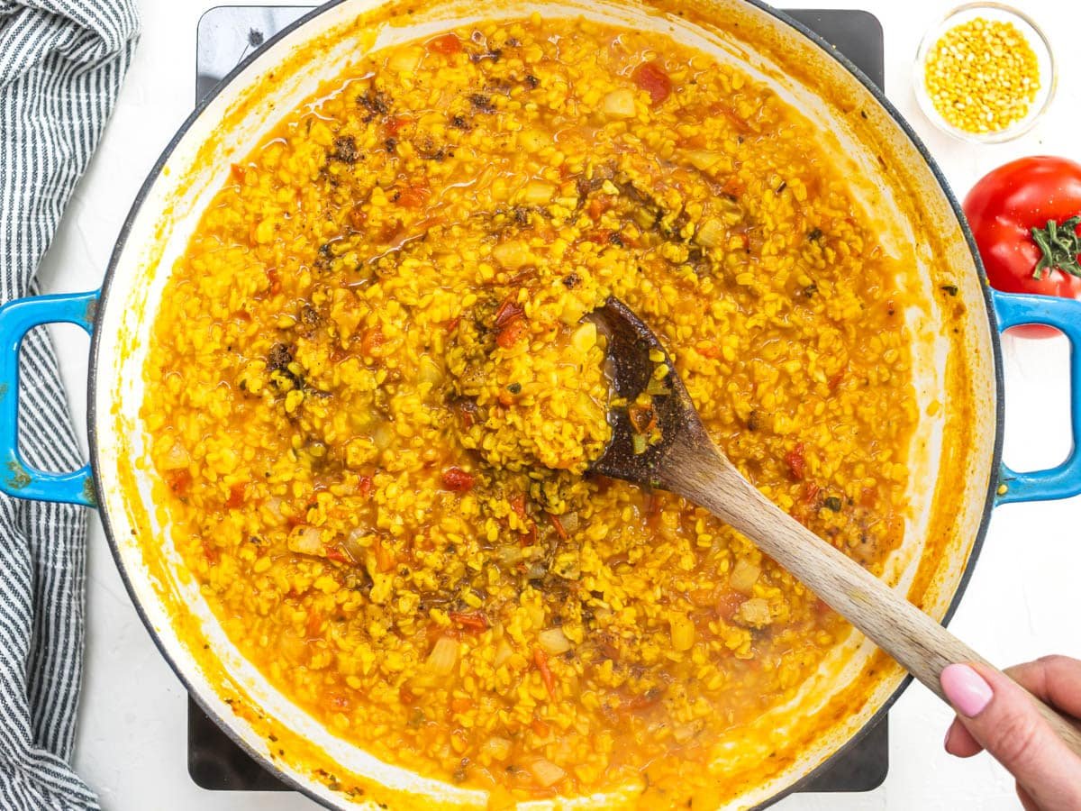 Mung Dal with chana masala and hand holding a wooden spoon
