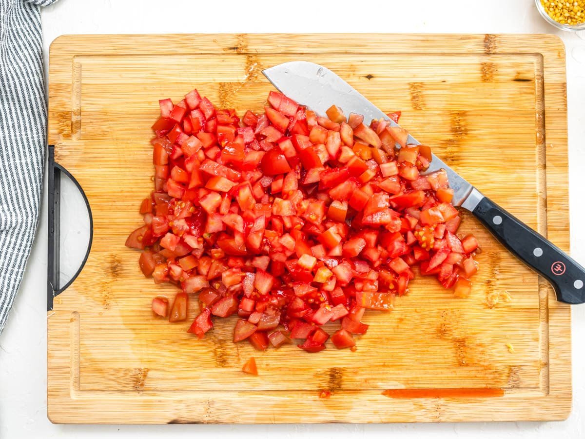 chopped vine tomatoes on a cutting board with a knife