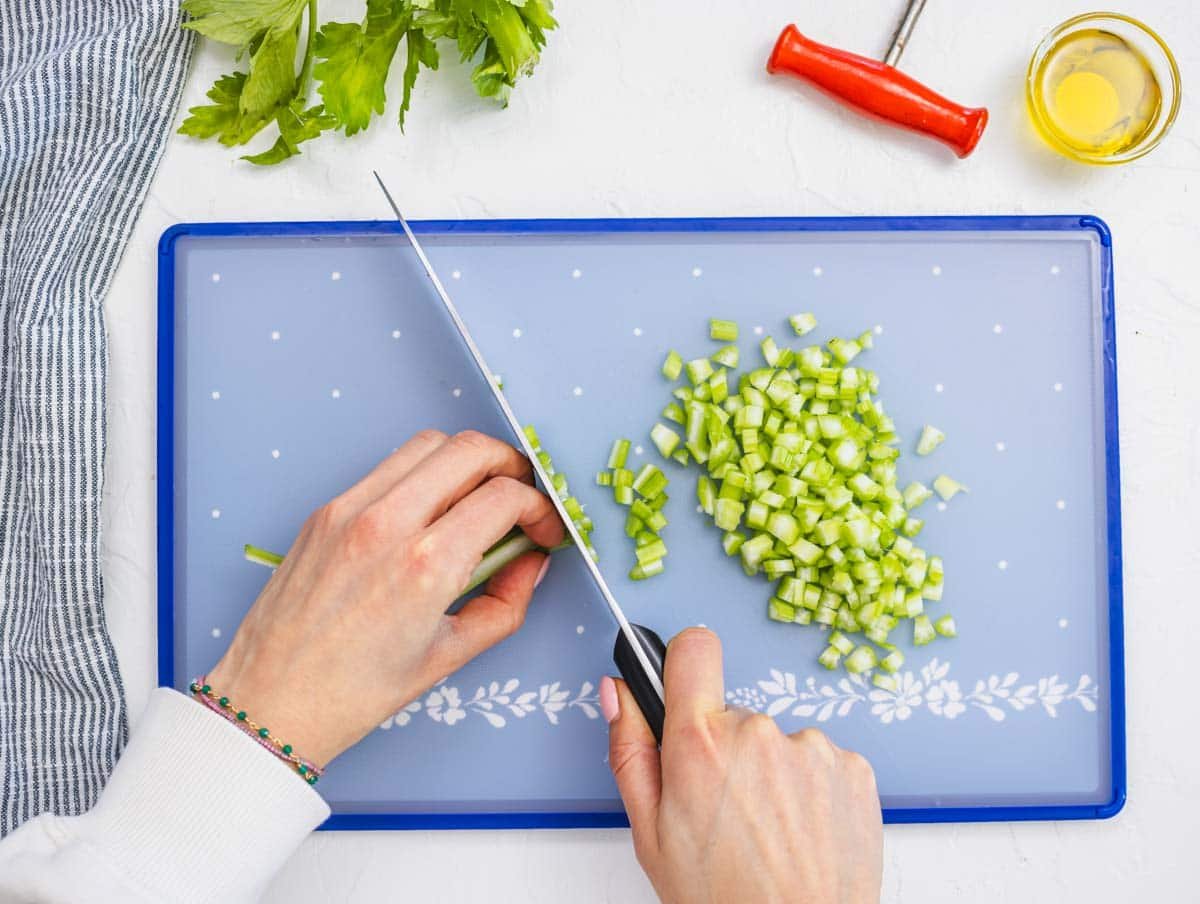 female hands chopping celery on a cutting board
