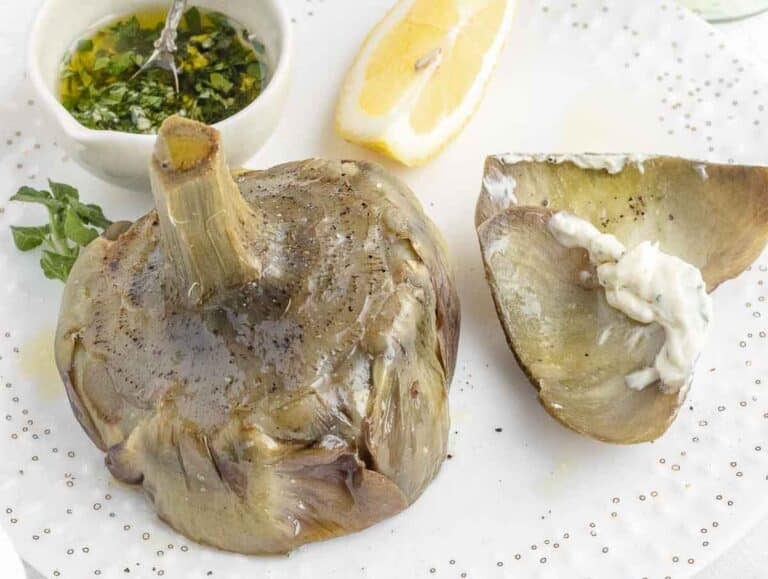 Steamed artichoke with vegan mayonnaise on a plate