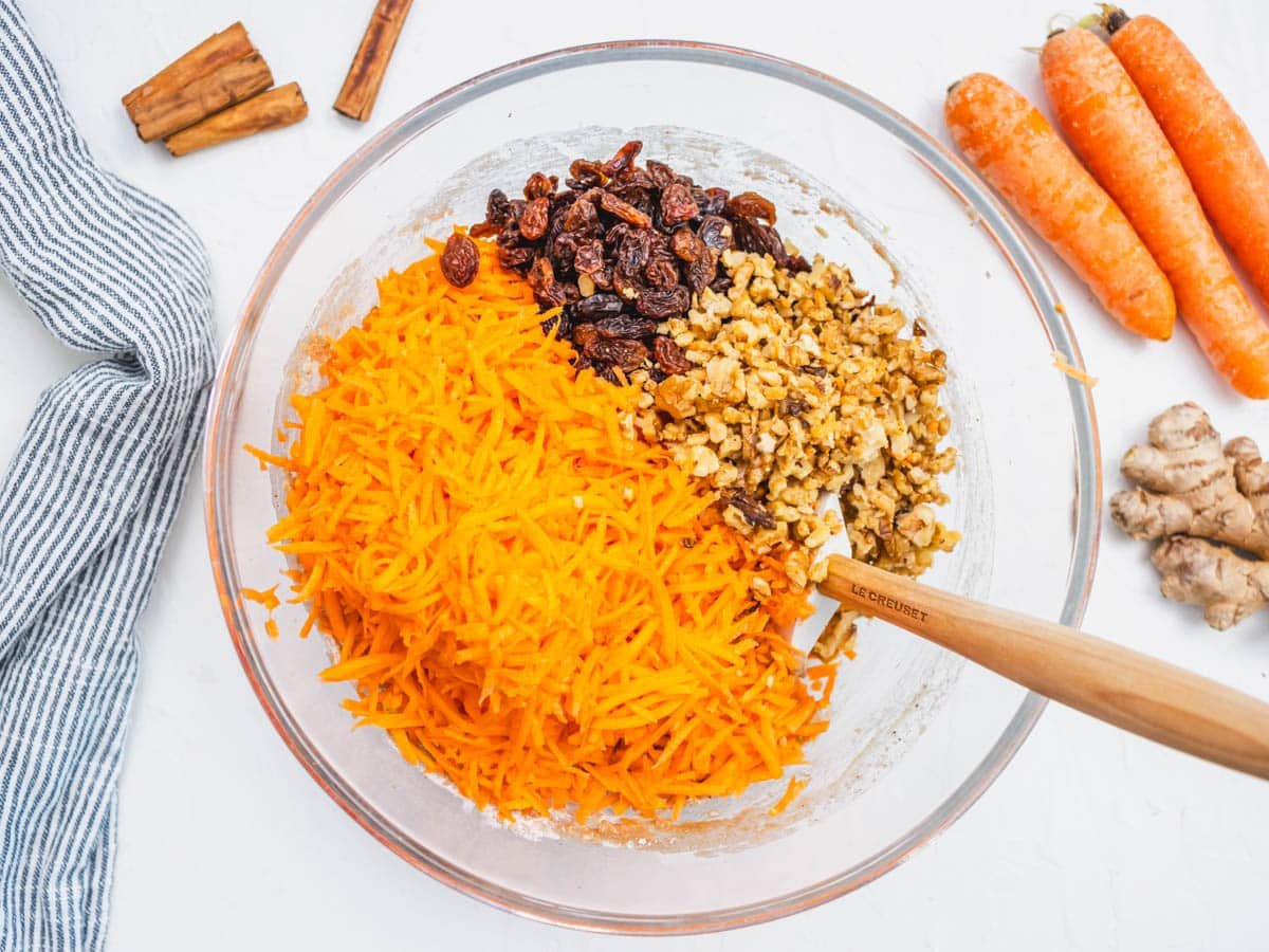 grated carrots, raisins, and walnuts in a glass bowl