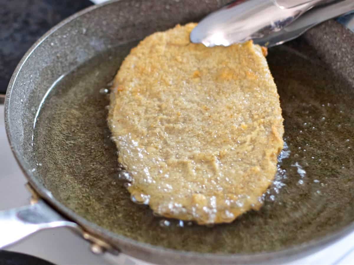 Vegan schnitzel frying in a skillet