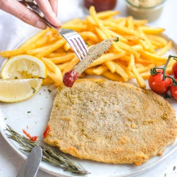 Vegan Schnitzel on a plate with fries and lemon wedges