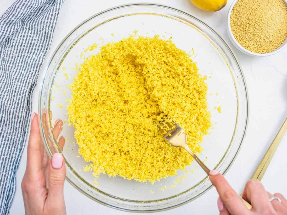 hands fluffing up couscous with a fork