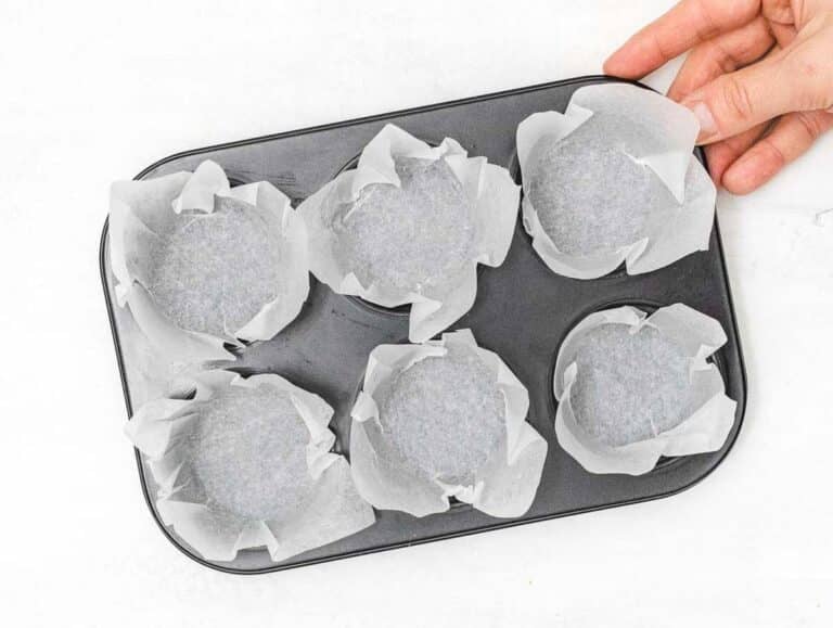 muffin pan with baking paper and a hand