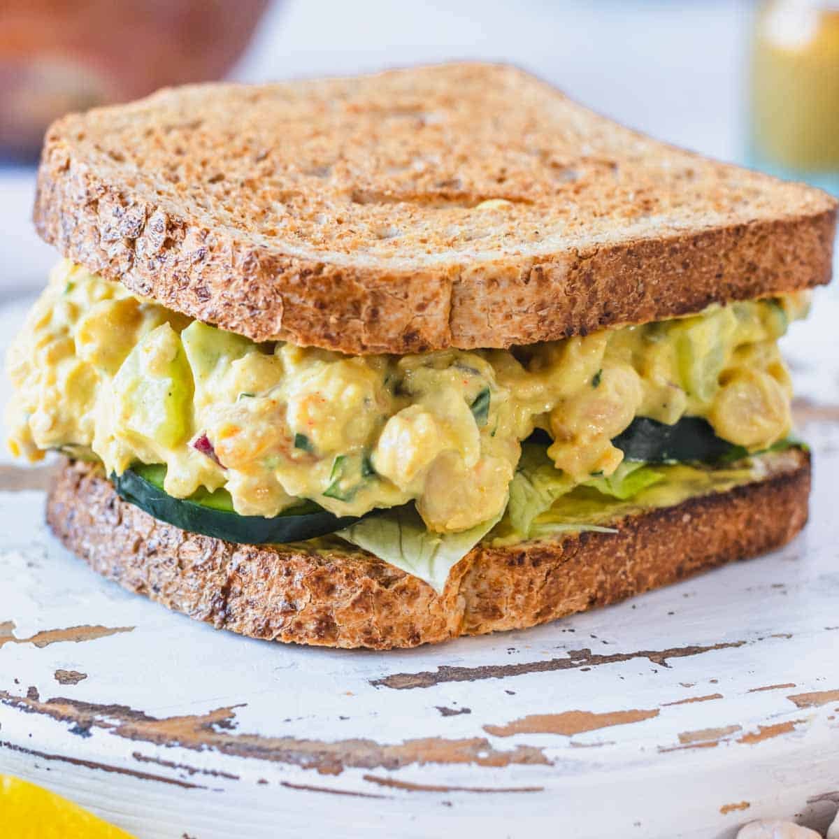 Curry chickpea salad in a sandwich with cucumber slices